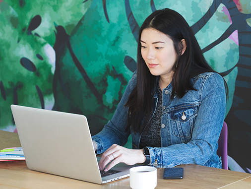 Woman at Laptop reading about How Composable Technology Powers Digital Disruption